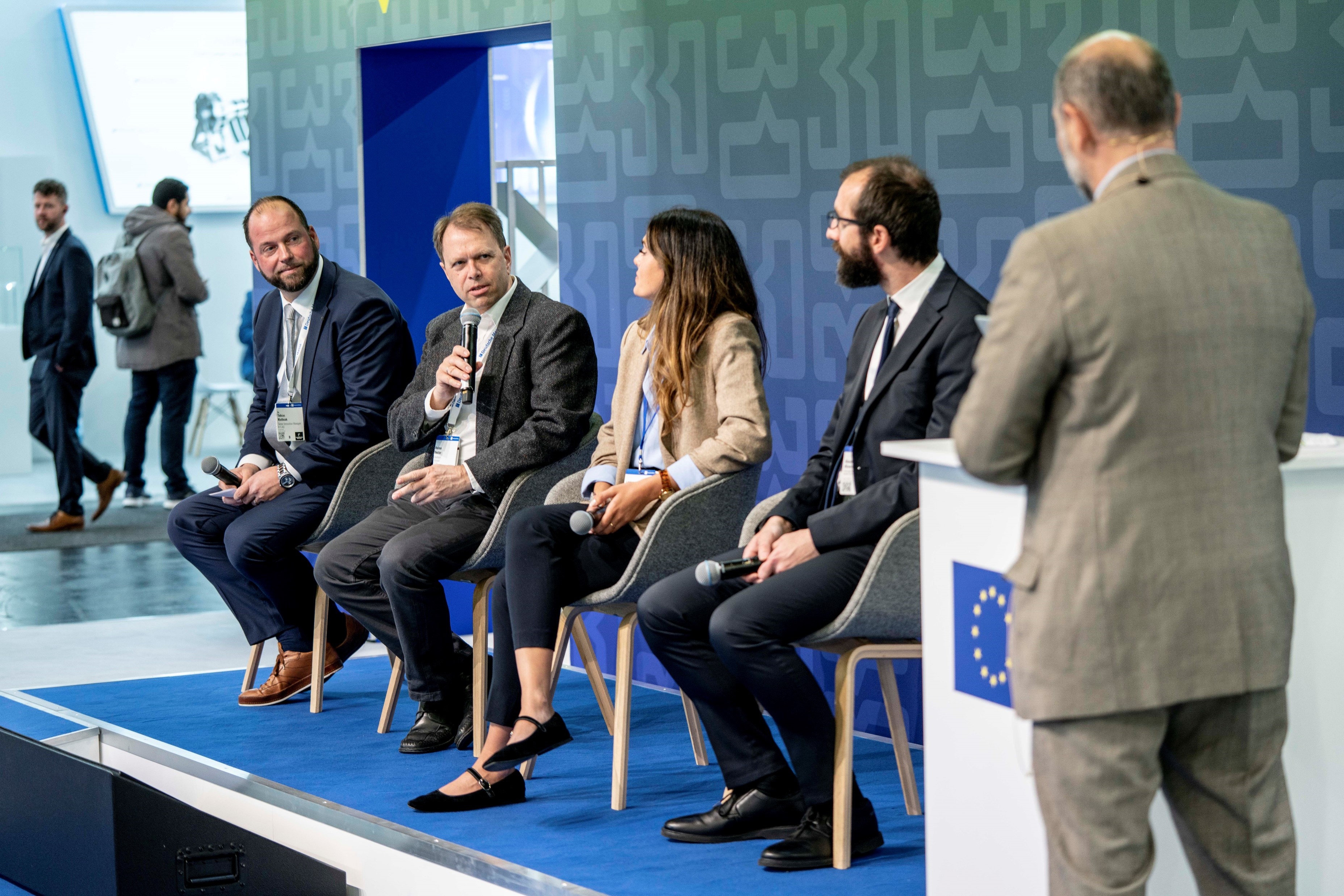 Panel discussion of four people at the podium of the stand