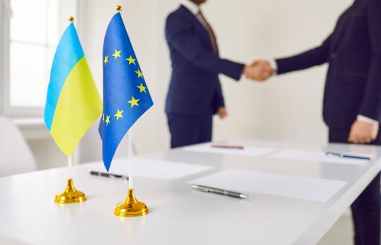 Flags of Ukraine and EU against background of representatives of countries shaking hands