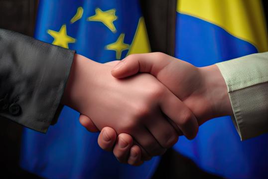 Handshake between 2 people with EU and Ukraine flags in background