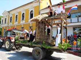 Tractor with a folkloric wagon with a wooden house and people