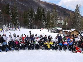Group photo of skiers on the slopes with trees and snow in the background
