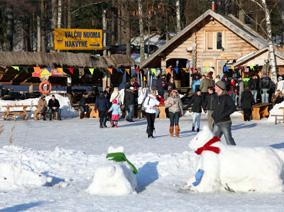 Snowmen and people in the background with a mountain hut