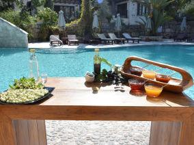 Wooden table with traditional food and products and a swimming pool in the background
