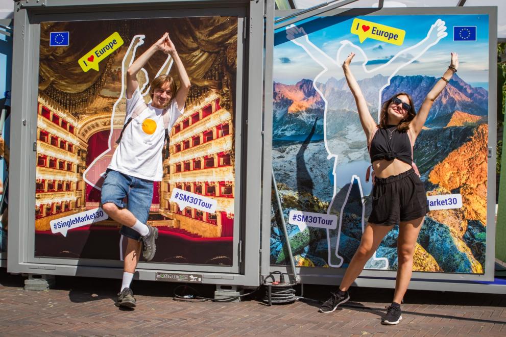 Two persons posing in front of a picture wall