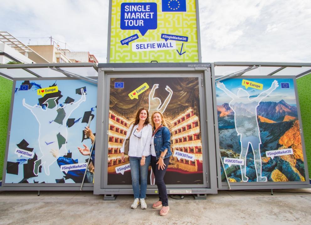 Two women in front of the photo wall