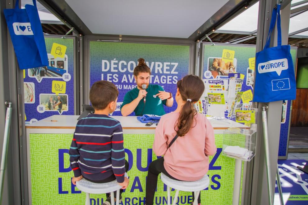 Man explaining something to two children at the Tour booth