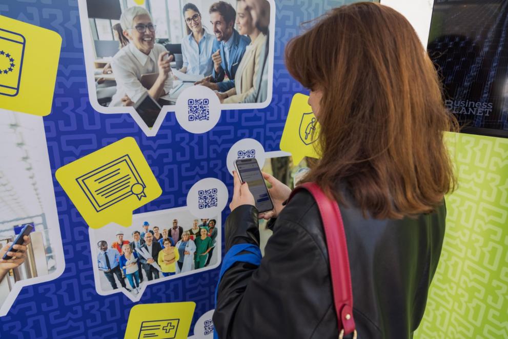 Woman scanning a QR code printed on the Tour booth wall