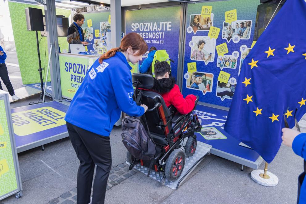 Staff assisting a person on an electric wheelchair who wants to visit the booth