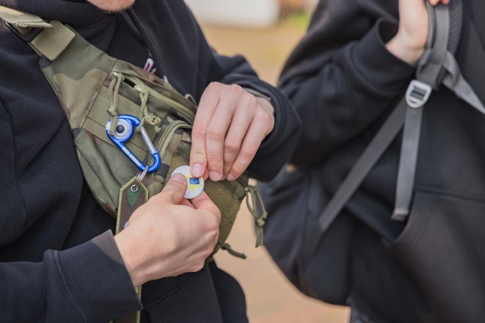 Close-up on someone attaching an EU pin to the backpack