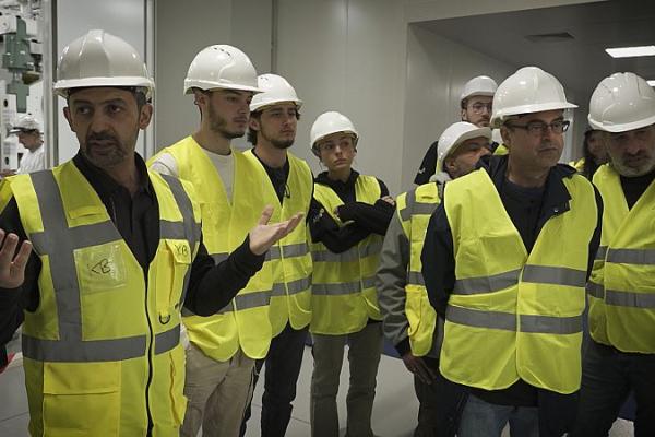 Business planet on green workforce for net zero energy goals: Still of workers in hard hats and yellow vests inside battery manufacturing facility
