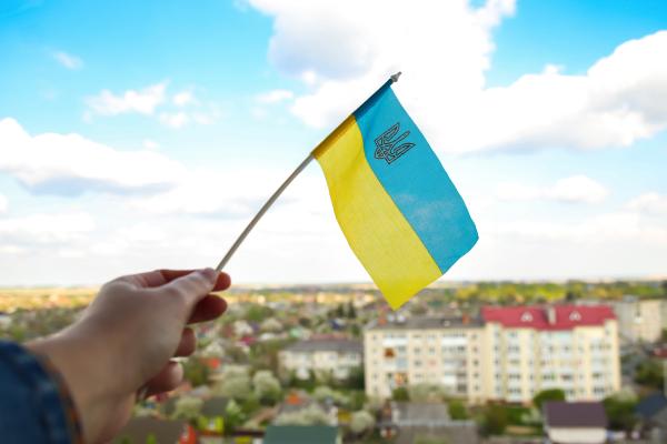 Hand holding Ukrainian flag with city in background